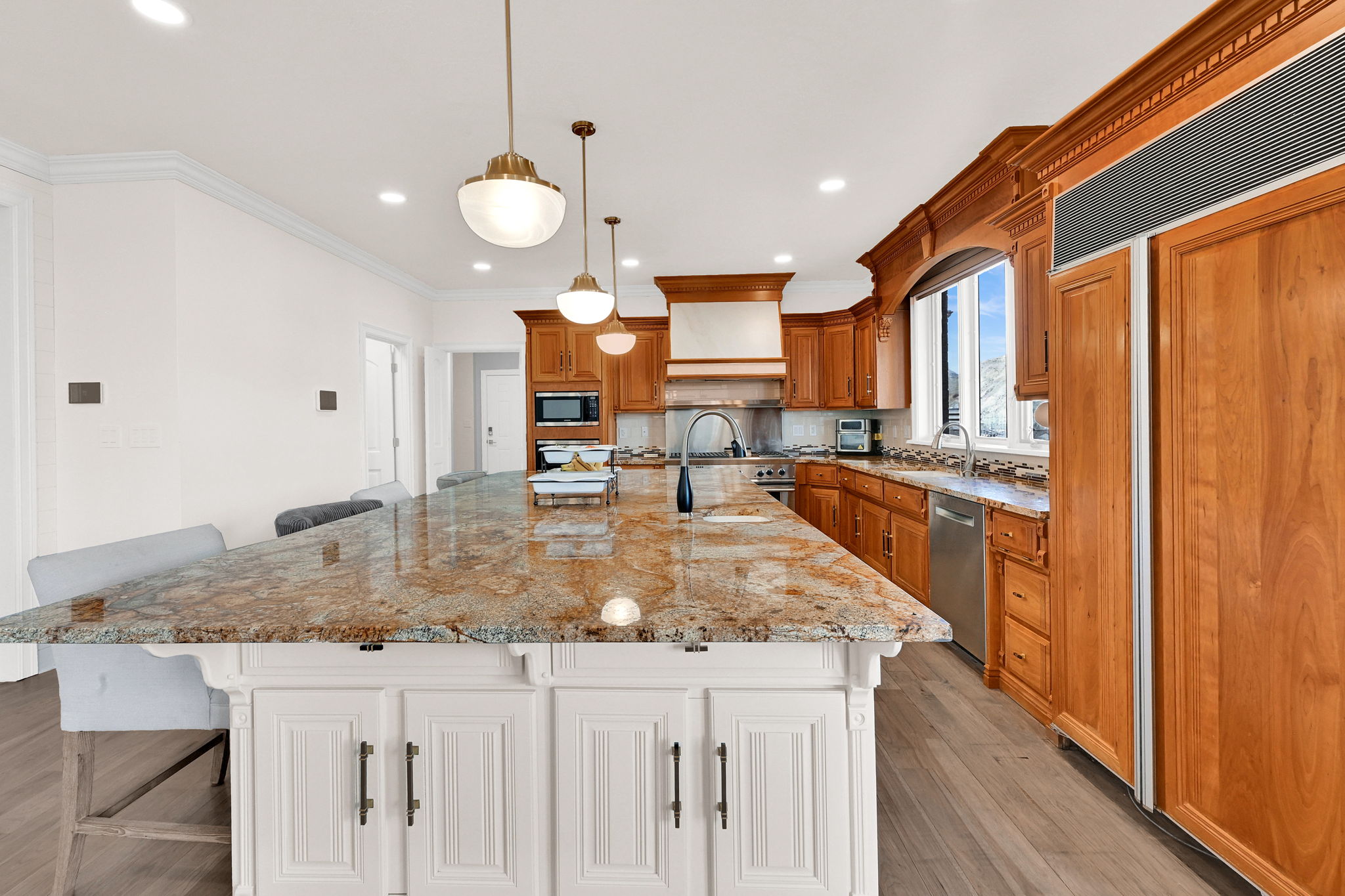 Chef kitchen with granite island, custom wood cabinetry, and integrated appliances